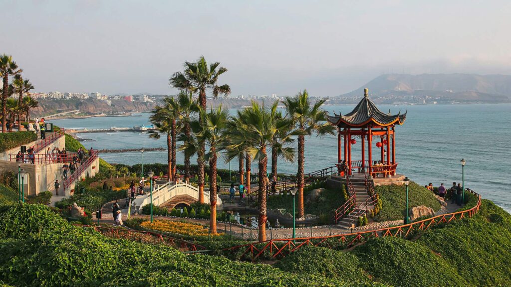 Scenic view of Parque Chino in Lima, Peru, featuring a red pagoda, palm trees, ocean views.
