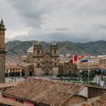 Panoramic view of Cusco, Peru's Plaza de Armas featuring historic colonial architecture, red tile roofs.