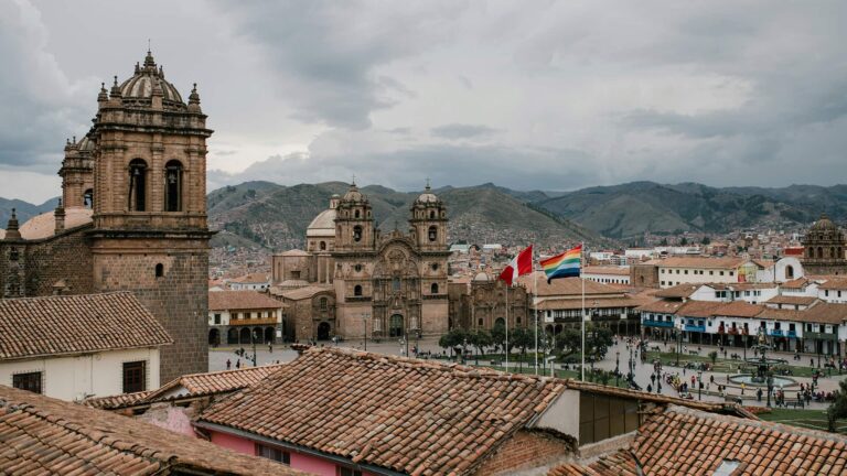 Panoramic view of Cusco, Peru's Plaza de Armas featuring historic colonial architecture, red tile roofs.